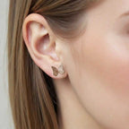 Gold Whisper butterfly earrings worn by a person with blond hair.