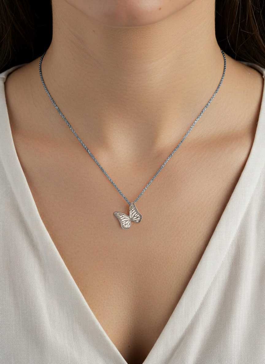 Silver Whisper butterfly necklace with an oxidized chain on a person wearing a white top