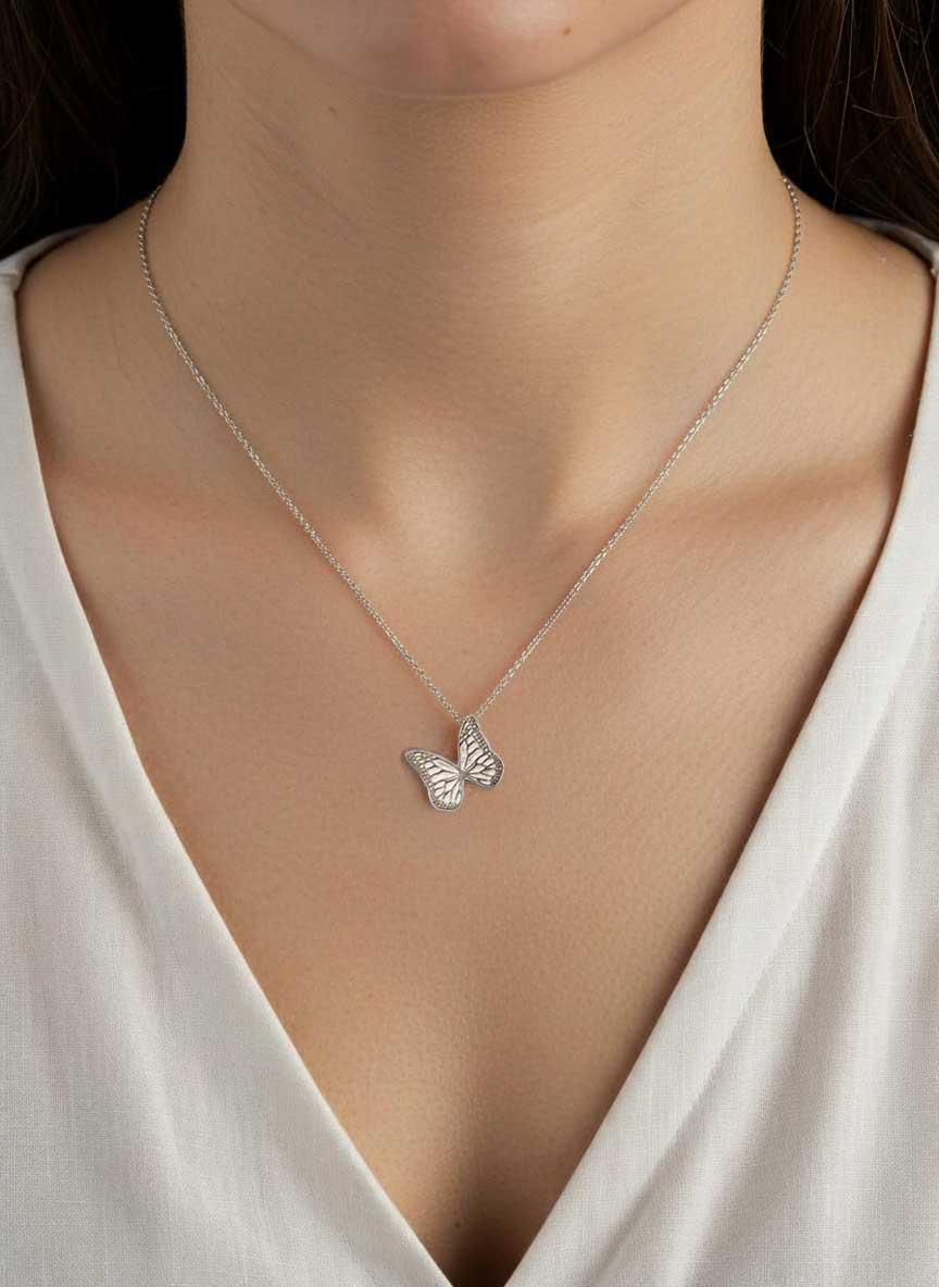 Silver Whisper butterfly necklace on a person wearing a white top