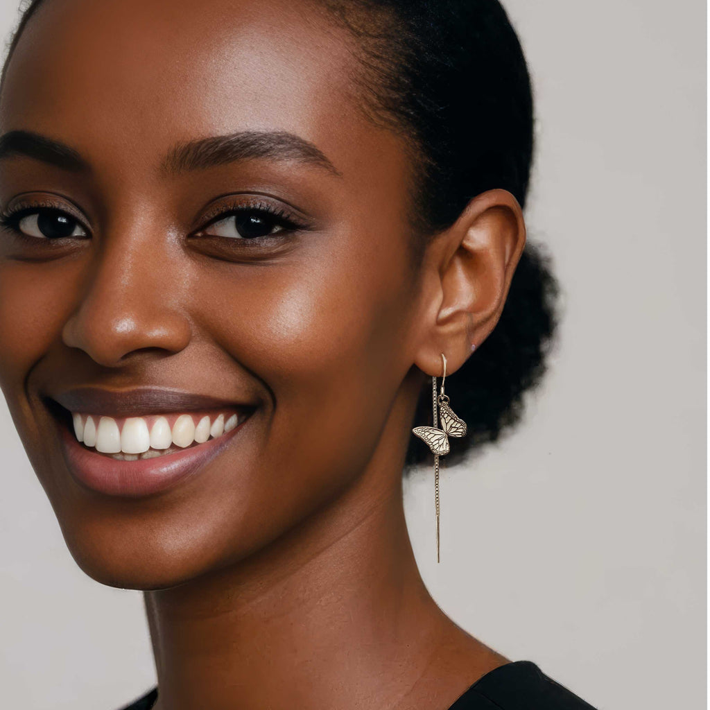 Woman wearing hand made monarch butterfly silver threader earrings with a neutral background | Camille Torres Designs