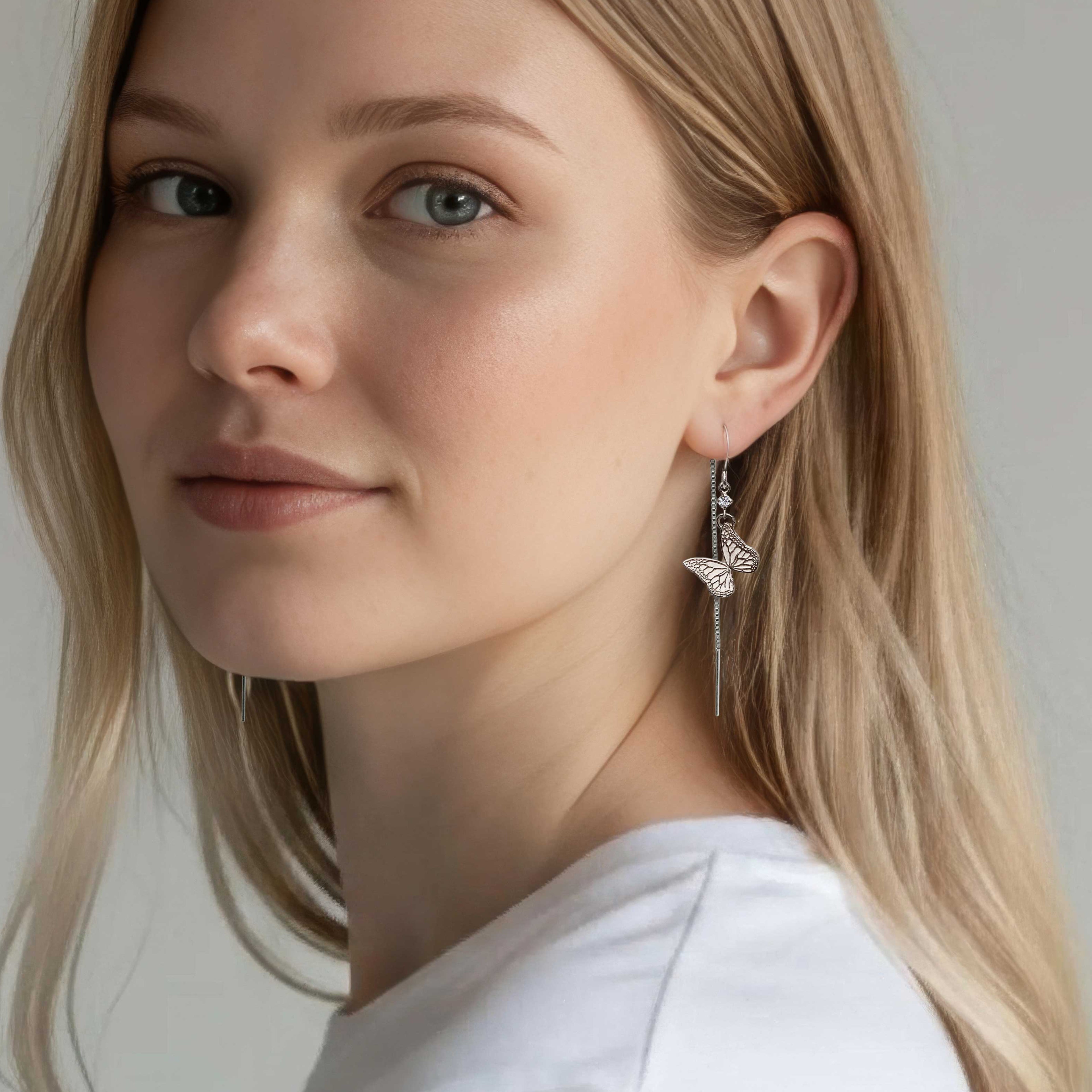 Woman wearing silver and diamond butterfly threader earrings against a neutral background | Camille Torres Designs